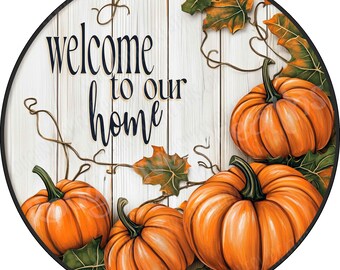 May include: A round sign with a white wood-plank background featuring the black text "welcome to our home" in a script and serif font. The design includes three orange pumpkins and green and orange autumn leaves with thin brown vines.