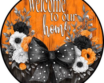 May include: A round sign featuring a wood-plank background in orange and dark brown. The text "welcome to our home" is printed in white. A large black bow with white polka dots sits at the bottom, surrounded by black, white, and orange flowers.