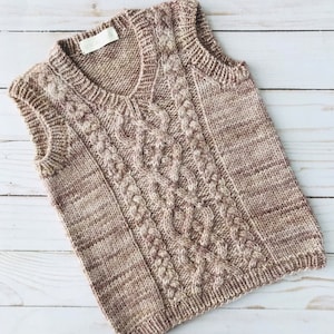 Puede incluir: Un chaleco sin mangas de punto marrón y beige con un patrón de trenza.