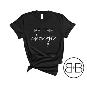 May include: Black t-shirt with white text that reads "BE THE change" in a cursive font.