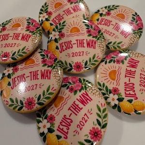 Puede incluir: Un conjunto de seis chapas redondas con fondo crema y un borde de flores y limones. Cada chapa muestra un gráfico de un sol naciente y el texto en rojo JESUS-THE WAY 2027, rodeado de flores de color rosa y blanco.