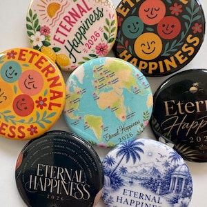 Può includere: Una collezione di sette spille rotonde con vari design. Alcune riportano la scritta Eternal Happiness 2026, mentre altre presentano motivi floreali, faccine sorridenti colorate, una mappa del mondo con cuori o un paesaggio blu e bianco.