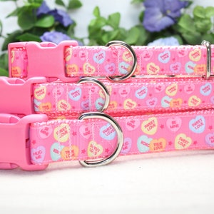 Puede incluir: Cuatro collares para perros de color rosa con anillas en D plateadas y hebillas de pl&aacute;stico rosa. Los collares est&aacute;n decorados con un patr&oacute;n rosa y blanco de corazones de caramelo con varios mensajes, entre ellos "Sweet Love", "True Love", "Hug Me" y "Be Mine".