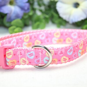 Puede incluir: Collar de perro rosa con un patr&oacute;n de corazones de caramelo de amor dulce. El collar tiene un anillo en D de metal plateado y una hebilla de pl&aacute;stico rosa.