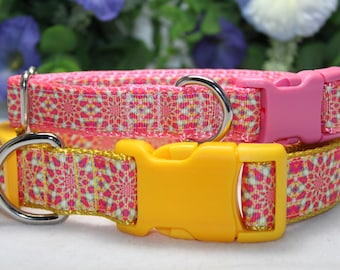 Puede incluir: Dos collares para perros con un patrón geométrico rosa y amarillo. El collar superior tiene una hebilla rosa y el collar inferior tiene una hebilla amarilla. Ambos collares tienen anillas en D de metal plateado.