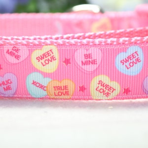 Puede incluir: Cinta rosa con un patr&oacute;n repetido de corazones coloridos con mensajes del D&iacute;a de San Valent&iacute;n como "Sweet Love", "Be Mine", "Hug Me" y "True Love".