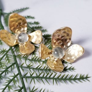 Peut inclure: Une paire de boucles d'oreilles en forme de fleur dorées avec une pierre précieuse transparente au centre de chaque fleur.