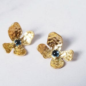 Peut inclure: Une paire de boucles d'oreilles en forme de fleur dorées avec des accents de pierres précieuses bleues.