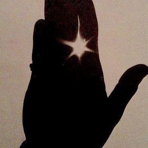 Peut inclure: Silhouette noire d'une main ouverte avec une étoile blanche brillante au centre. Les doigts sont légèrement courbés. Le fond est de couleur beige clair.