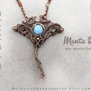 Puede incluir: Un colgante de alambre de cobre con forma de manta raya con una piedra preciosa azul en el centro. El colgante está colgado de una cadena de cobre. La imagen incluye el texto "Manta Ray Wire Wrapped Pendant".