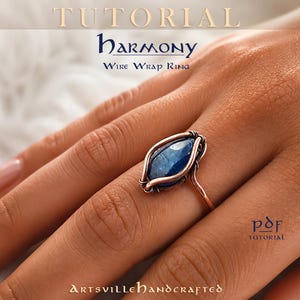 May include: A copper wire wrap ring featuring a central marquise-cut blue stone. The text reads: TUTORIAL HARMONY WIRE WRAP RING, PDF TUTORIAL, and ARTSVILLEHANDCRAFTED. The ring is worn on a finger, showcasing the intricate metal wire design.