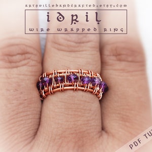 May include: A copper wire wrapped ring with a row of purple beads. The ring is on a finger.