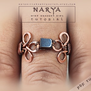 Puede incluir: Un anillo de alambre de cobre envuelto con una piedra negra en el centro. El anillo está en un dedo y el texto "NARYA wire wrapped ring TUTORIAL" está por encima del anillo. El texto "PDF TUTORIAL" está en la esquina inferior derecha de la imagen.