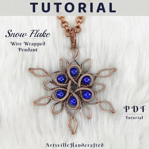 Puede incluir: Un colgante de copo de nieve envuelto en alambre de cobre con seis cuentas azules. El colgante está sobre una superficie blanca y peluda. El texto "Snowflake Wire Wrapped Pendant" y "PDF Tutorial" es visible en la imagen.
