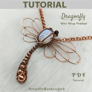 Può includere: Un ciondolo a forma di libellula in filo di rame con un cabochon di pietra di luna e perline nere. Il ciondolo è su una catena di rame. L'immagine include il testo "Dragonfly Wire Wrap Pendant" e "PDF Tutorial".