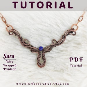 May include: A copper wire wrapped pendant necklace with a blue gemstone. The pendant is in the shape of a stylized 'Y' with a loop at the top for attaching a chain. The necklace is on a white furry surface. The text 'Sara Wire Wrapped Pendant' and 'PDF Tutorial' is visible below the necklace.