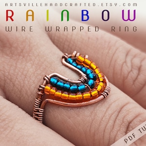 Puede incluir: Anillo de alambre envuelto en arcoíris con cuentas naranjas y azules. El anillo está en un dedo. El texto "RAINBOW WIRE WRAPPED RING" está en la parte superior de la imagen. El texto "PDF TUTORIAL" está en la parte inferior de la imagen.