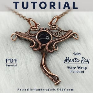 Könnte beinhalten: Ein kupferdrahtgewickelter Anhänger in Form eines Mantarochens mit einem schwarzen Stein in der Mitte. Der Anhänger liegt auf einer weißen, flauschigen Oberfläche. Der Text "Baby Manta Ray Wire Wrap Pendant" befindet sich unter dem Anhänger. Der Text "PDF Tutorial" befindet sich in der linken unteren Ecke des Bildes.
