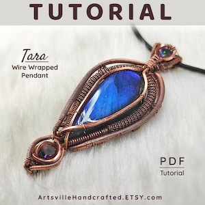 May include: A handcrafted wire-wrapped pendant with a teardrop-shaped blue stone center. The pendant is made with copper-colored wire and features a tutorial. The text "Tara Wire Wrapped Pendant" is displayed. The Etsy shop name is ArtsvilleHandcrafted.ETSY.com.