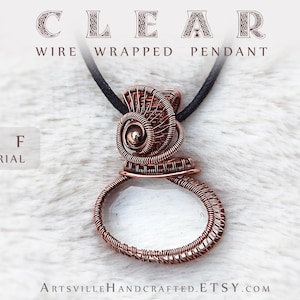 Puede incluir: Un colgante envuelto en alambre de cobre con un centro de vidrio transparente. El colgante está unido a un cordón negro. El texto "CLEAR WIRE WRAPPED PENDANT" y "PDF TUTORIAL" son visibles en la imagen.