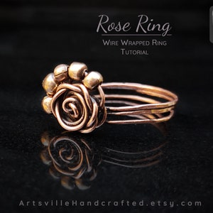 May include: A copper wire wrapped ring with a rose design and small copper beads. The ring is on a black surface. "Rose Ring" and "Wire Wrapped Ring Tutorial" are written above the ring.