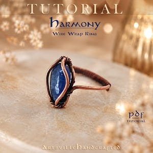 Könnte beinhalten: Ein Drahtwickelring mit einem zentralen ovalen blauen Stein, der von Kupferdraht umschlossen ist. Der Text TUTORIAL HARMONY WIRE WRAP RING und PDF TUTORIAL ARTSVILLEHANDCRAFTED ist sichtbar. Der Ringband besteht aus gewickeltem Kupferdraht.