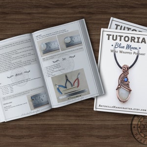 Puede incluir: Un tutorial para hacer un colgante envuelto en alambre con una piedra de luna azul y una piedra preciosa azul. El tutorial se titula "Colgante envuelto en alambre Blue Moon" e incluye una lista de materiales y pasos. El colgante se muestra en la imagen.