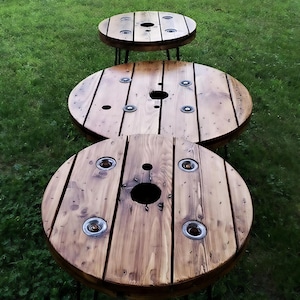 May include: Three wooden round tables with black metal legs. The tables are made from reclaimed wood and have a rustic look.