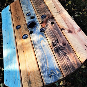 May include: A round wooden table top with a blue and brown wood grain pattern. The table top has a circular hole in the center and is marked with the text "SR 127 1/2" in black.