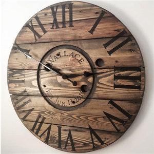 May include: A large wooden clock with Roman numeral markings and a personalized inscription that reads "Wallace Est. Jun. 13, 2017".