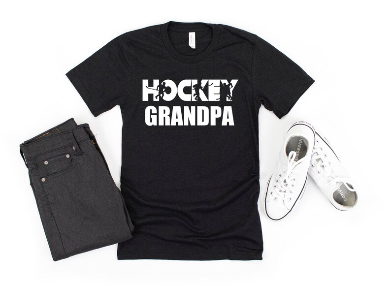 May include: Black t-shirt with white text that reads "HOCKEY GRANDPA" with hockey player silhouettes in the letters.