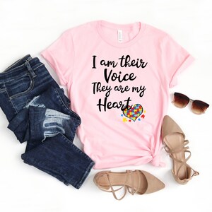 K&ouml;nnte beinhalten: Rosa T-Shirt mit dem Text "I am their Voice They are my Heart" und einem herzf&ouml;rmigen Puzzle-Motiv.
