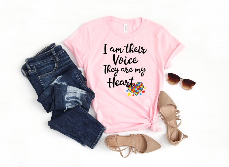 K&ouml;nnte beinhalten: Rosa T-Shirt mit dem Text "I am their Voice They are my Heart" und einem herzf&ouml;rmigen Puzzle-Motiv.