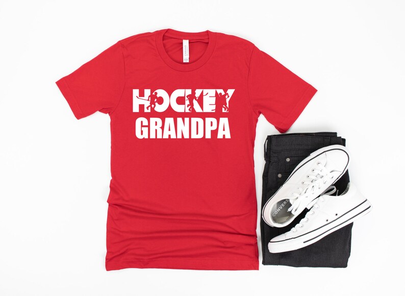 May include: Red t-shirt with white text that says "Hockey Grandpa" with a graphic of hockey players in the word "Hockey".