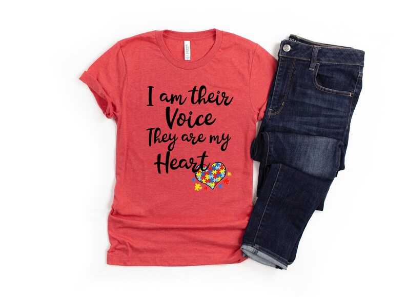 K&ouml;nnte beinhalten: Rotes T-Shirt mit dem Text "I am their Voice They are my Heart" und einem Herz aus Puzzle-Teilen in Blau, Gelb und Gr&uuml;n.