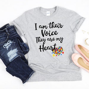 K&ouml;nnte beinhalten: Ein graues T-Shirt mit dem Text "Ich bin ihre Stimme Sie sind mein Herz" und einem herzf&ouml;rmigen Puzzle-St&uuml;ck-Design.