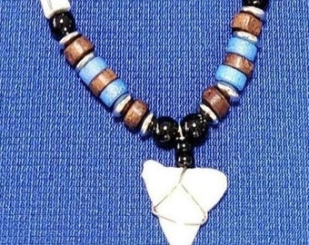 May include: A necklace with brown, blue, and black beads and a white shark tooth pendant.