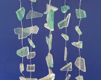 May include: A sea-themed wind chime with a starfish at the top and multiple strands of light green glass pieces hanging from it.