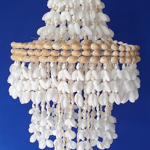 Puede incluir: Una lámpara de araña de conchas blancas y marrones con varios niveles de conchas colgando de un marco de alambre.