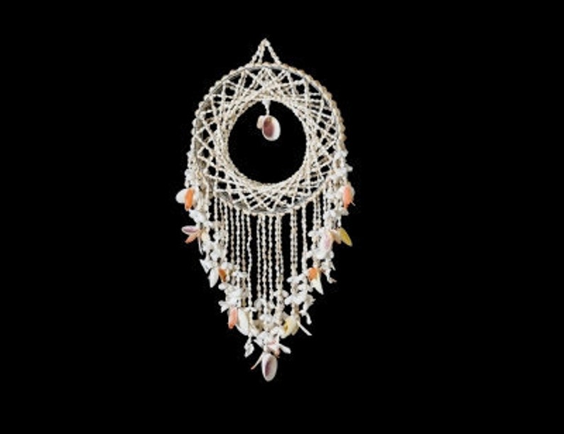 May include: A white dream catcher with a circular woven base and a long fringe of white beads and seashells. The fringe is decorated with small pink and orange seashells.
