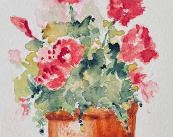 May include: Watercolor painting of a potted plant with vibrant red and pink flowers and green foliage. The terracotta pot sits on a neutral surface. The artist's signature, "Kathy Glangeli," is visible at the bottom.