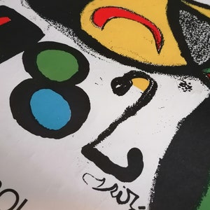 May include: A black and white abstract design with a yellow, red, and green circle. The design includes the number "82" and the word "Spain" in black lettering.