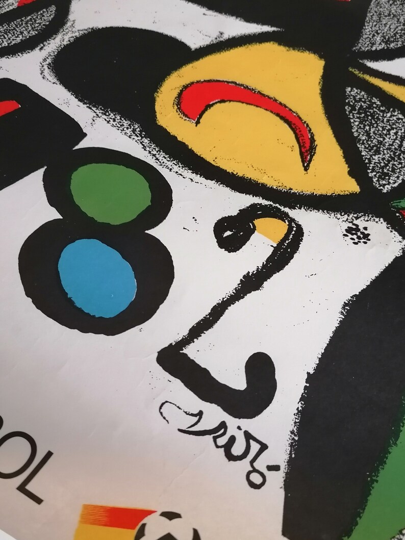 May include: A black and white abstract design with a yellow, red, and green circle. The design includes the number "82" and the word "Spain" in black lettering.