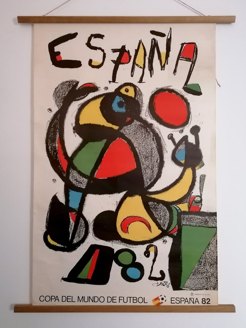 May include: A vintage poster for the 1982 FIFA World Cup in Spain. The poster features a colorful abstract design with a red, yellow, green, and blue figure holding a ball. The text "ESPA&Ntilde;A 82" and "COPA DEL MUNDO DE FUTBOL" is at the bottom of the poster.