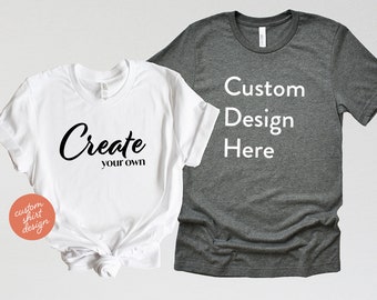 May include: Two t-shirts, one white and one gray. The white t-shirt has the text "Create your own" printed on it. The gray t-shirt has the text "Custom Design Here" printed on it.
