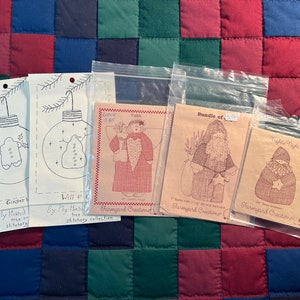 May include: Five different craft patterns for making ornaments and figures. The patterns are printed on brown paper and feature illustrations of a gingerbread man, a Santa Claus, an angel, and a snowman. The patterns are titled "Gingerbread", "Will F", "Bundle of", "Fath", and "Fight Night".