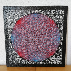 Könnte beinhalten: Abstrakte Malerei mit einem roten und blauen kreisförmigen Design auf einem strukturierten schwarz-weißen Hintergrund. Das Kunstwerk zeigt einen zentralen roten Kreis mit komplizierten blauen Linien, vor einem schwarzen Rand mit einem gesprenkelten Muster.