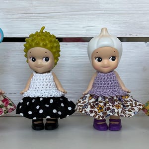 Puede incluir: Cuatro peque&ntilde;as figuras, cada una con un sombrero y un atuendo &uacute;nicos. Las figuras tienen diferentes sombreros: un rat&oacute;n azul, pelo verde puntiagudo, un ajo blanco y un hipop&oacute;tamo rosa. Cada figura lleva un top de ganchillo y una falda floral o de lunares.