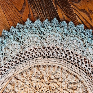 Pu&ograve; includere: Un centrino all'uncinetto circolare con un intricato motivo a mandala. Il centro &egrave; beige chiaro, che sfuma in un delicato gradiente di blu-verde tenue sul bordo esterno smerlato. Il design presenta punti densi e lavorazione a pizzo.