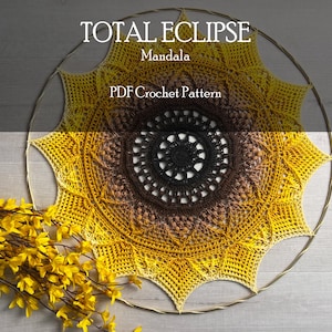 May include: A crochet mandala pattern in a sunflower design with a brown, yellow, and black colour gradient. The pattern is called "Total Eclipse Mandala" and is a PDF crochet pattern.